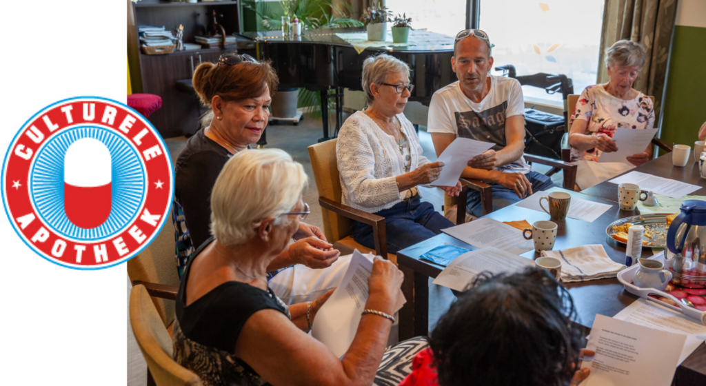 A Culturele Apotheek event: people around a table reading from sheets of paper